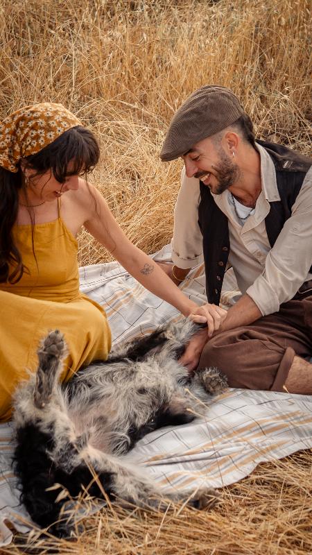 זוג צוחק ומלטף כלב על מפת פיקניק — צילומי זוגיות עם כלב