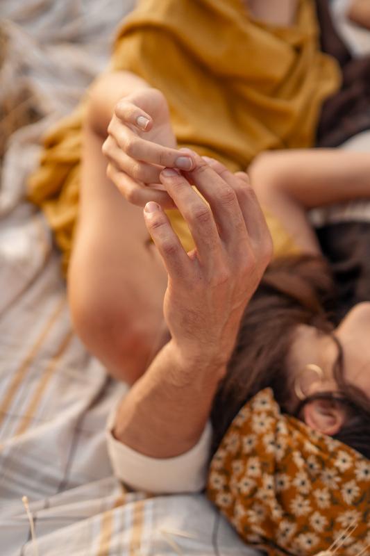 אצבעות נוגעות זו בזו על מפת פיקניק — פרט מצילומי זוגיות