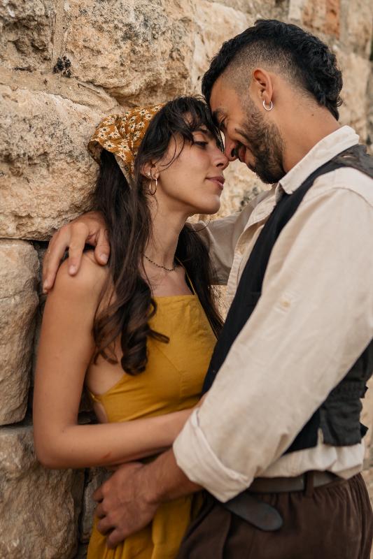 זוג נוגע מצח במצח ליד קיר אבן עתיק — צילומי זוגיות אינטימיים