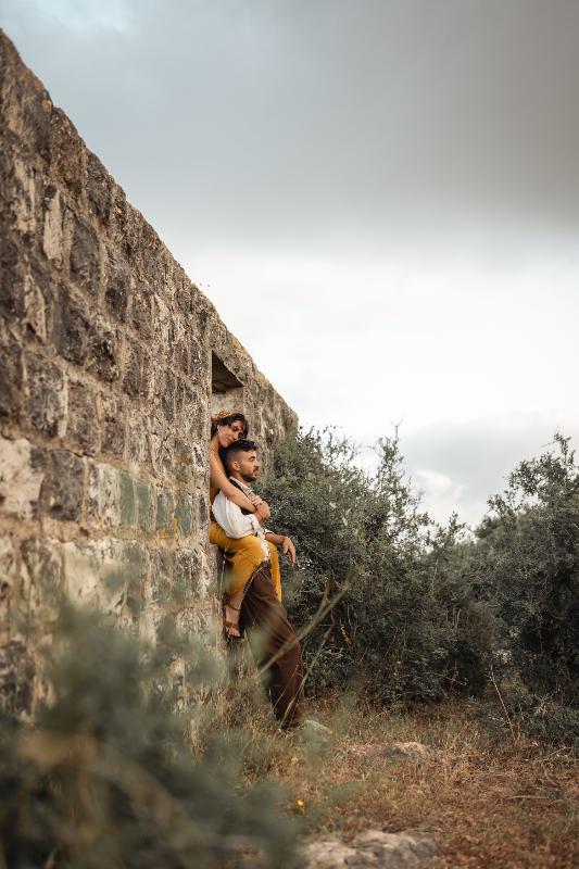 זוג מחובק בחלון קיר אבן עתיק בין שיחים — צילומי זוגיות