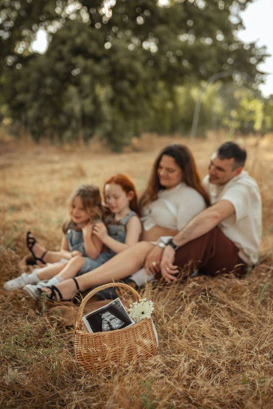 משפחה עם ילדים בצילומי הריון בשדה בשקיעה