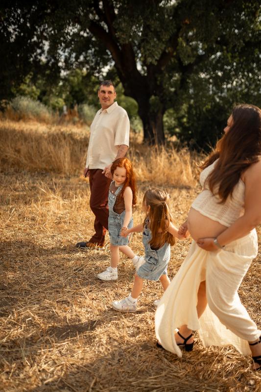 משפחה הולכת בשדה קש זהוב תחת עץ אלון – צילומי הריון עם ילדים
